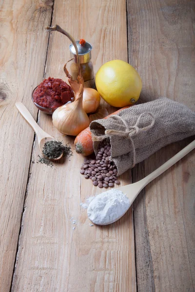 Groat derrama fora do saco e legumes e ervas em uma madeira — Fotografia de Stock