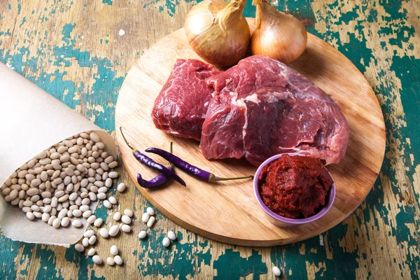 Carne fresca cruda, frijol blanco y verduras en una mesa de madera vieja — Foto de Stock