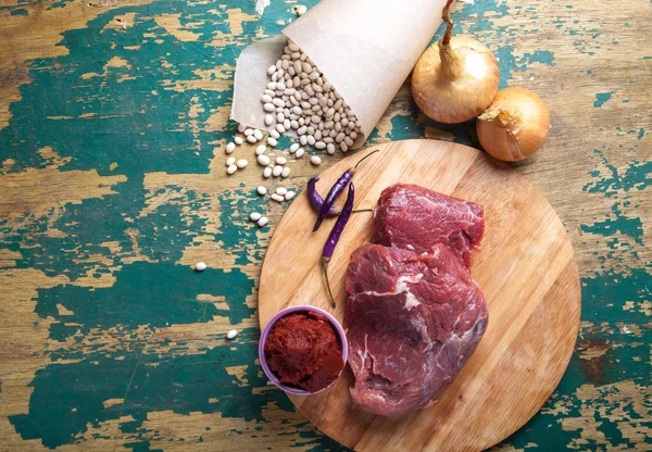 Carne fresca cruda, frijol blanco y verduras en una mesa de madera vieja — Foto de Stock