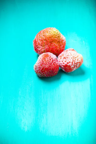 Frozen strawberries on a blue wooden cutting board. Selective fo — Stock Photo, Image