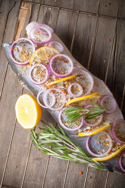 Fisk Nelma med citron, lök och rosmarin på ett träbord. Ton — Stockfoto