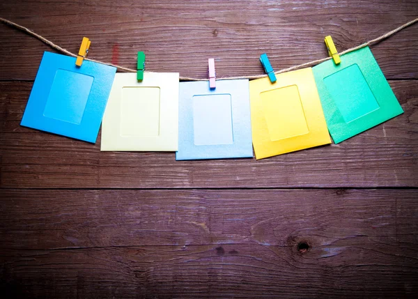 Colored clothespins with foto frames on rope on a wooden table o — Stockfoto