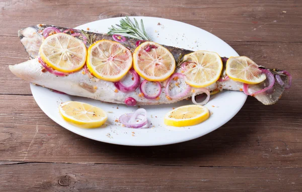 Fisk Nelma med citron, lök och rosmarin på ett träbord — Stockfoto