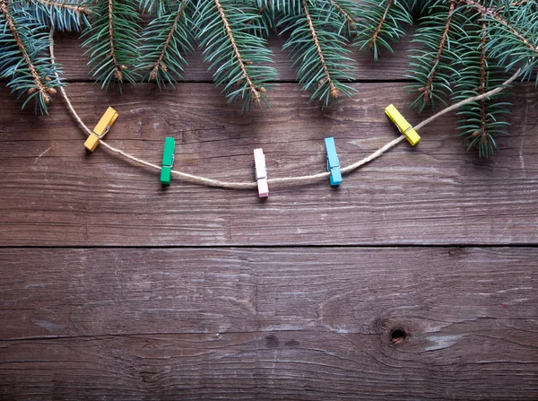 Ramo de árvore de Natal e clothspins na corda em uma mesa de madeira — Fotografia de Stock