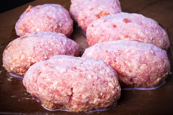 Frozen cutlets on a brown cutting board. Selective focus. Toned — Stock Photo, Image