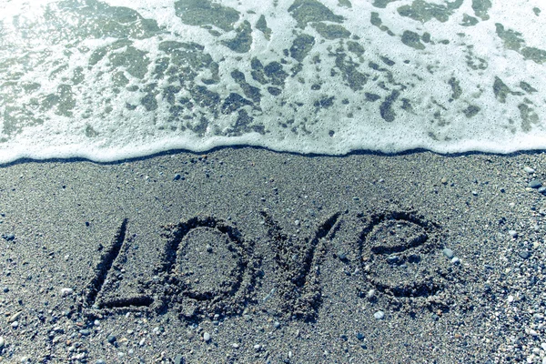 A inscrição "AMOR" em um litoral de areia molhada. Tonificado — Fotografia de Stock