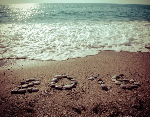 Napis "2016" przez mały kamyk na mokry piasek wybrzeża. T — Zdjęcie stockowe