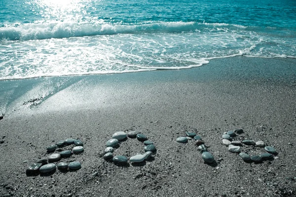 L'iscrizione "2016" di piccolo ciottolo su una spiaggia di sabbia bagnata. T — Foto Stock