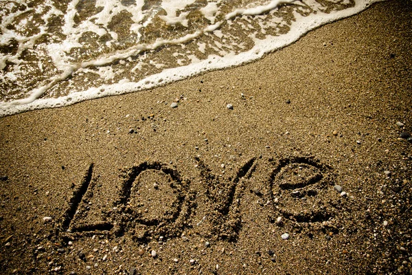 The inscription "LOVE" on a wet sand seacoast. Toned — Stock Photo, Image