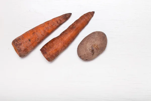 Gekochte Kartoffeln und Möhren auf einem weißen Holzbrett — Stockfoto