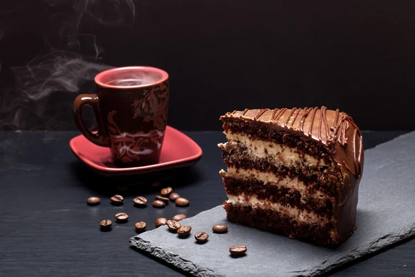 Ein Stück Schokoladenkuchen und eine Tasse Kaffee auf einem Schieferteller — Stockfoto