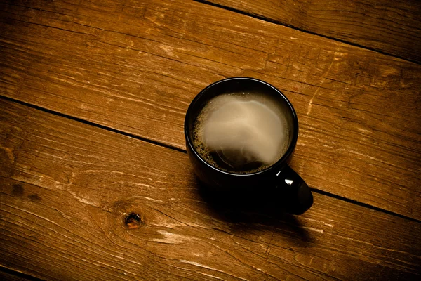 Черная чашка кофе на старом деревянном столе. Toned — стоковое фото