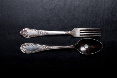 Metal çatal ve kaşık siyah bir zemin üzerine