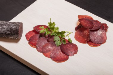 At sosis, otlar ve baharatlar kesme tahtası üzerinde dilimlenmiş. Tonda