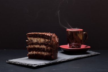 Bir parça çikolatalı kek ve kahve bl üzerinde kayrak plaka üzerinde