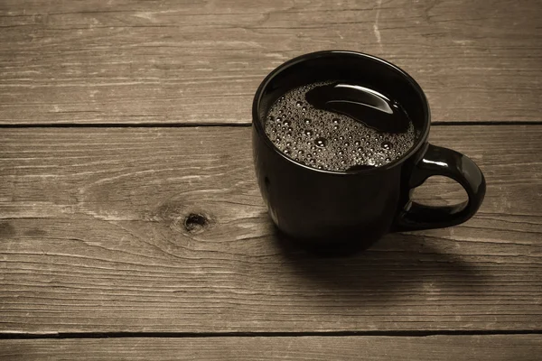 Xícara de café preto na velha mesa de madeira. Tonificado — Fotografia de Stock