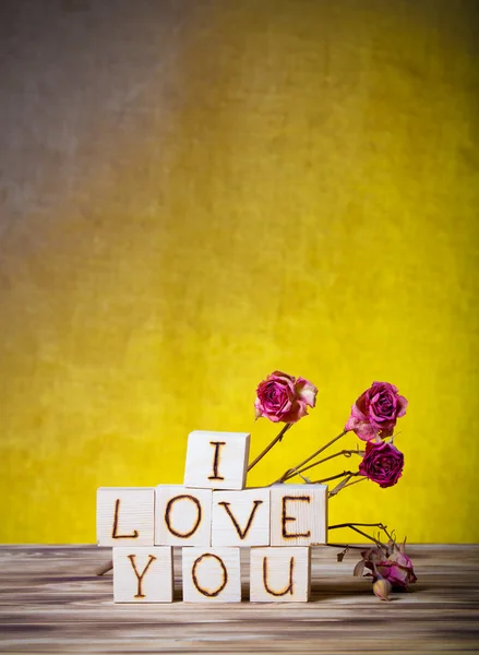 Cubos de madera y flores de rosas secas en un nuevo tablero de madera y arpillera — Foto de Stock