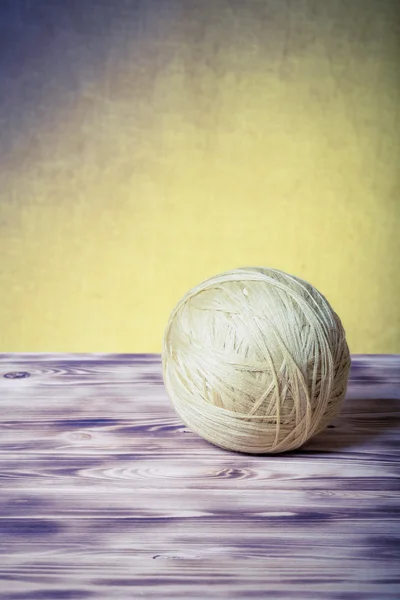 Clew of yarn on new wooden board and burlap background. Toned — Stock Photo, Image