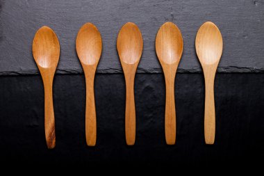 Tahta kaşıklar kayrak bir siyah arka plan üzerine bir tabak üzerinde