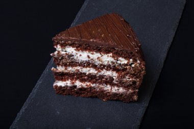 Siyah arka plan üzerine kayrak plaka üzerinde çikolatalı pasta bir parça