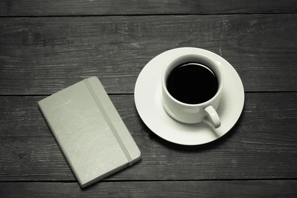 White cup of coffee and notebook on old wooden table. Toned — Stock Photo, Image