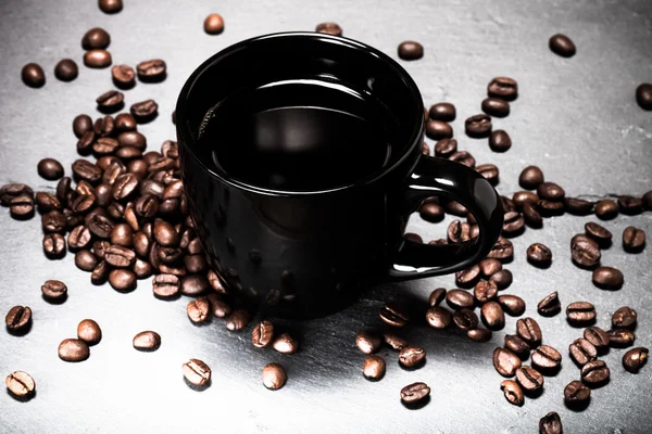 Svart kopp kaffe och kaffe frön på skiffer bakgrunden. Till — Stockfoto