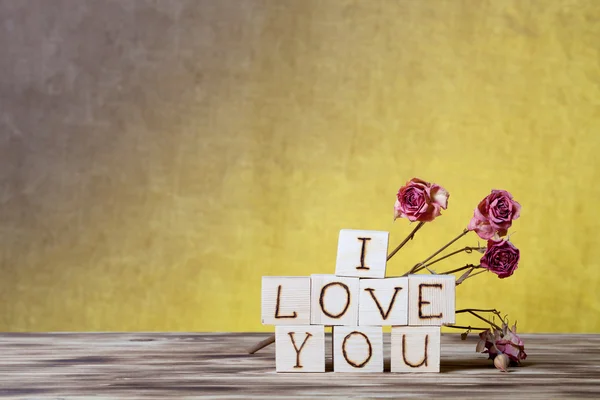 Cubos de madera y flores de rosas secas en un nuevo tablero de madera y arpillera — Foto de Stock