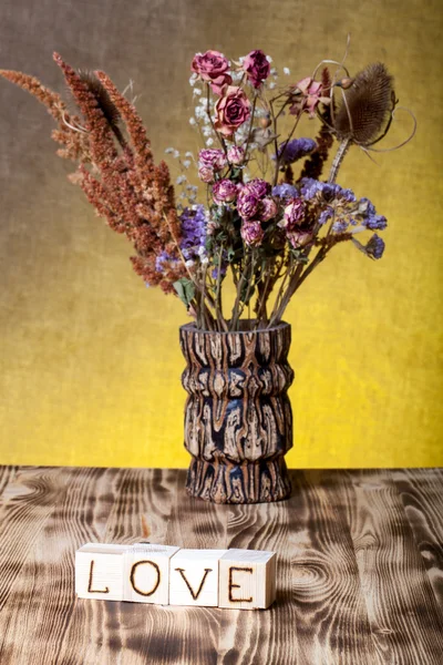 Cubos de madeira com inscrição "AMOR" e buquê de flores secas — Fotografia de Stock