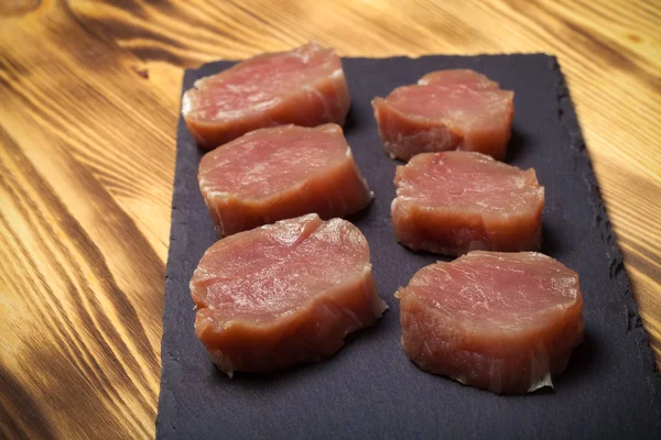 Pieces of raw meat on a plate of slate on a new burned wooden ba — Stock Photo, Image