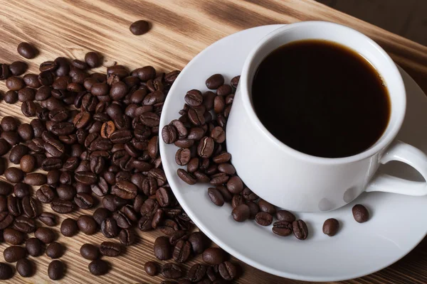 Koffiebonen en koffie in witte cup op houten tafel voor backgro — Stockfoto