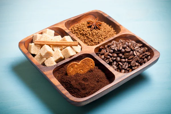 Diversi tipi di caffè su piatto di legno su tavolo blu. Tonica — Foto Stock