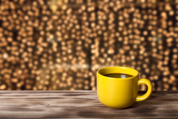 Kaffee in Tasse auf Holztisch vor verschwommenem Hintergrund — Stockfoto