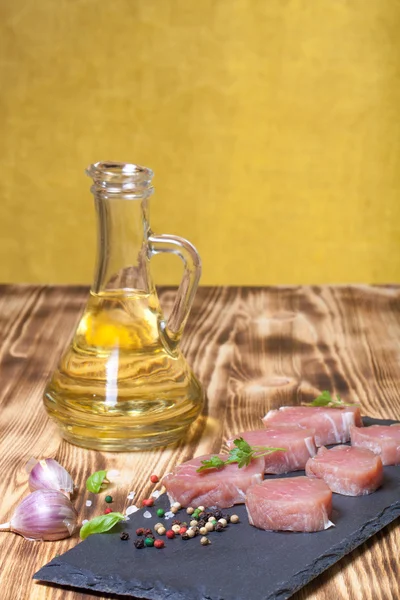 Raw meat with herbs and spices on a black slate plate on a woode — Stock Photo, Image