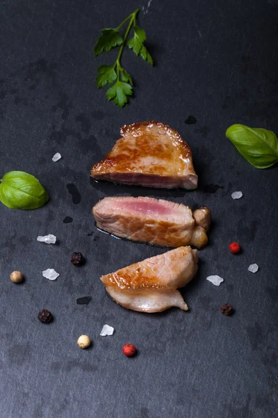 Carne fritta con erbe e spezie su un piatto di ardesia nera — Foto Stock