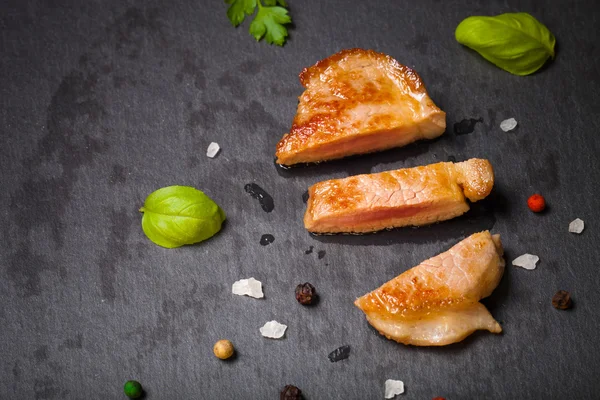 Carne frita con hierbas y especias en un plato de pizarra negra. Tonificado —  Fotos de Stock