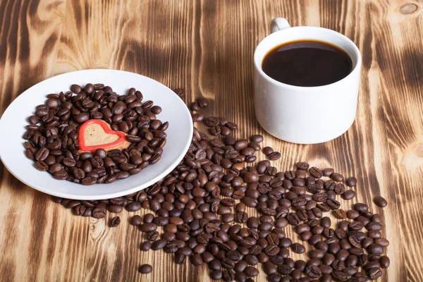 Kaffeebohnen und Kaffee in weißer Tasse auf Holztisch für Backgro — Stockfoto