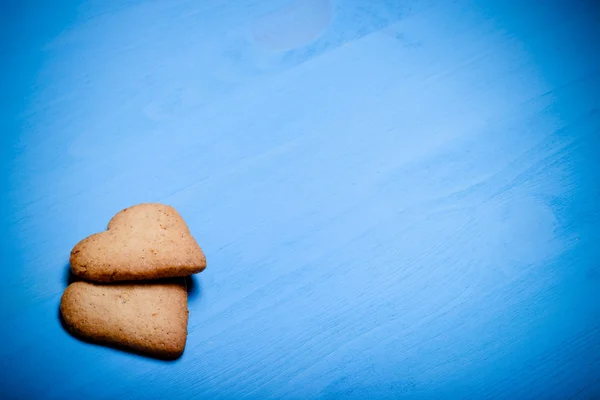 Dos galletas en forma de corazón en una mesa de madera azul. Tonificado —  Fotos de Stock