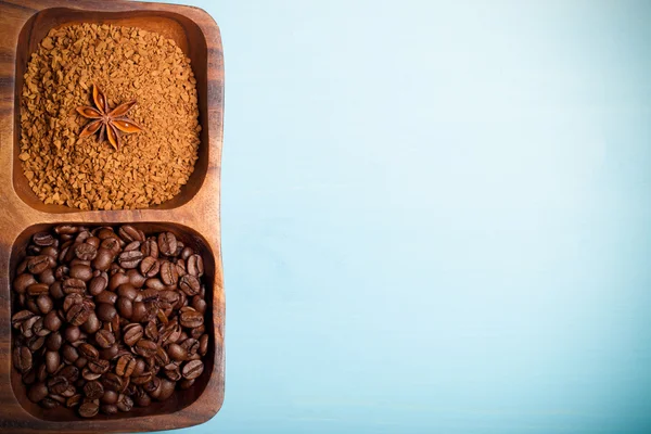 Diferentes tipos de café en plato de madera sobre mesa azul. Tonificado —  Fotos de Stock