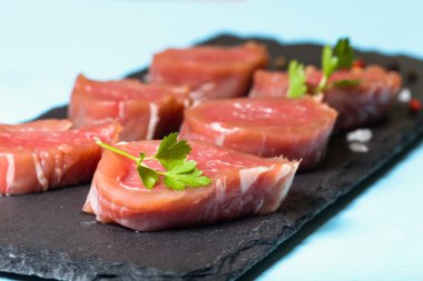 Otlar ve baharatlar mavi üzerinde siyah arduvaz tabakta çiğ et 