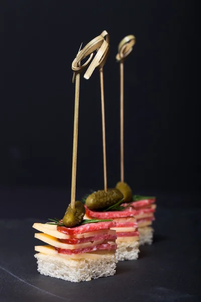 Small snacks canape with salami, cheese and pickle on skewer on — Stock Photo, Image