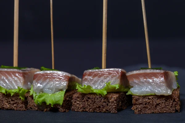 Små snacks KANAPE med sill, rågbröd, sallad och gröna o — Stockfoto