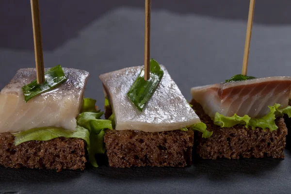 Piccolo snack tartina con aringhe, pane di segale, lattuga e verde o — Foto Stock