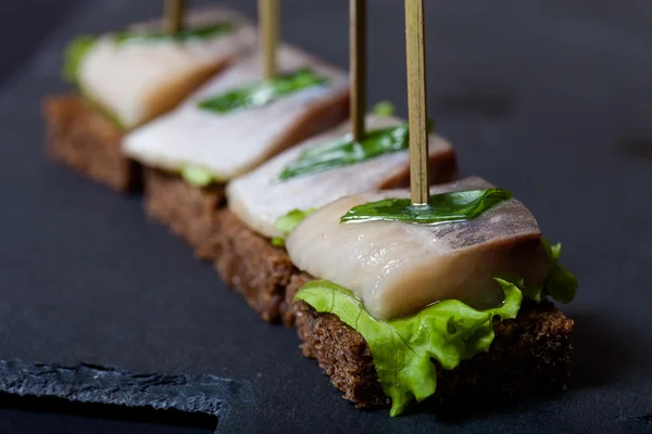 Piccolo snack tartina con aringhe, pane di segale, lattuga e verde o — Foto Stock