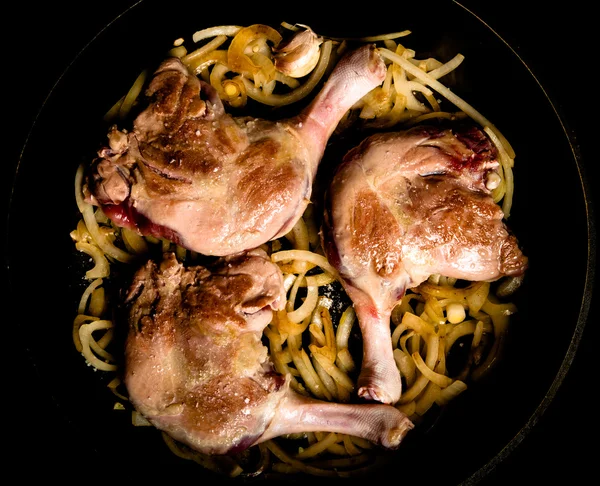 Duck legs fried in a pan with garlic and onion. Toned — Stock Photo, Image