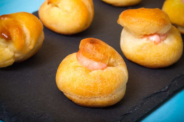 Jogo de pequenos profiteroles em uma chapa de ardósia preta. Profundidade superficial — Fotografia de Stock