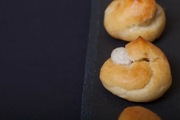 Uppsättning små profiteroles på en svart skiffer plåt. Selektiv tant — Stockfoto