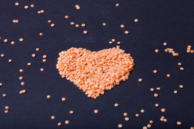 Turuncu mercimek siyah bir arka plan üzerinde bir kalp şeklinde. Seçici