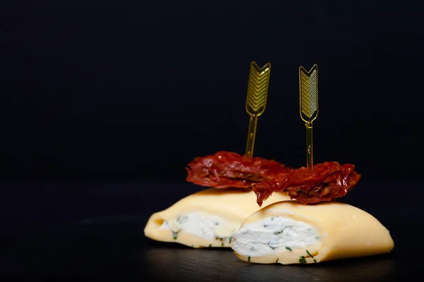 Kleine Rollen mit Käse und getrockneten Tomaten am Spieß auf einem schwarzen sl — Stockfoto