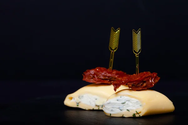 Pequeños rollos con queso y tomate seco en pincho sobre un sl negro — Foto de Stock