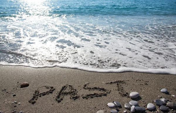 Onda e iscrizione "PAST" sulla costa ciottolosa del mare. Scelta — Foto Stock